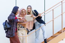 Three happy women looking at screen of digital tablet