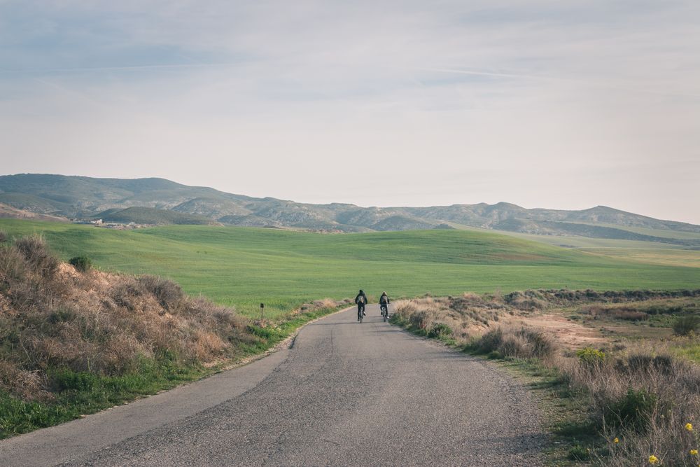Men riding bicycles on road in desert hills