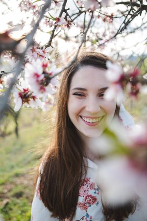 Young happy woman between trees in garden
