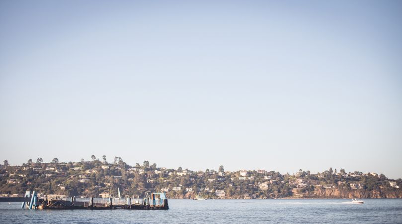 Ship floating on water near coast in sunny day