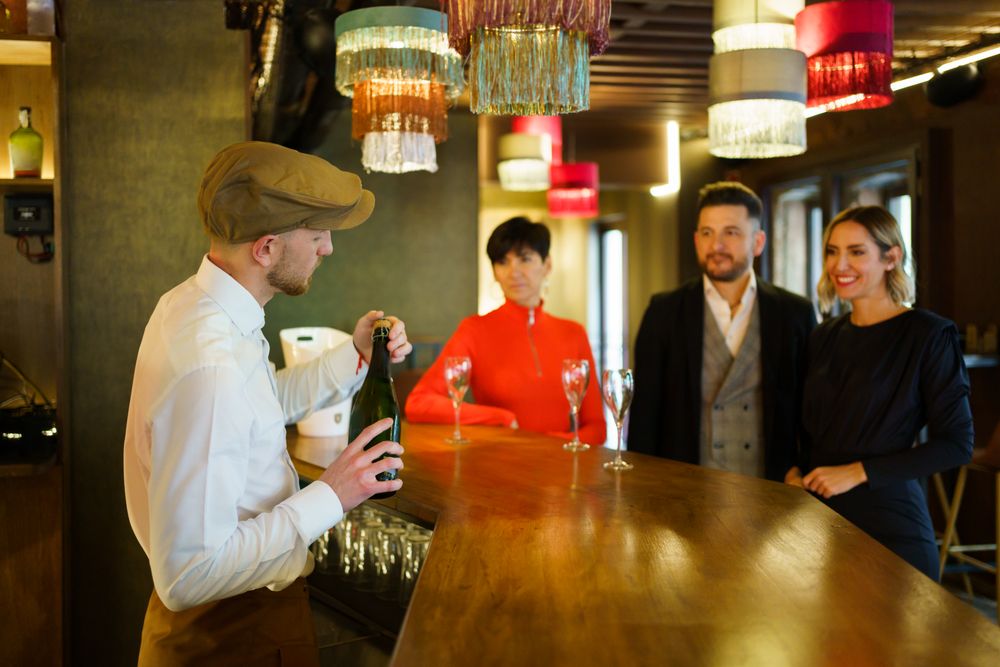 Bartender opening a bottle of bubbly customers