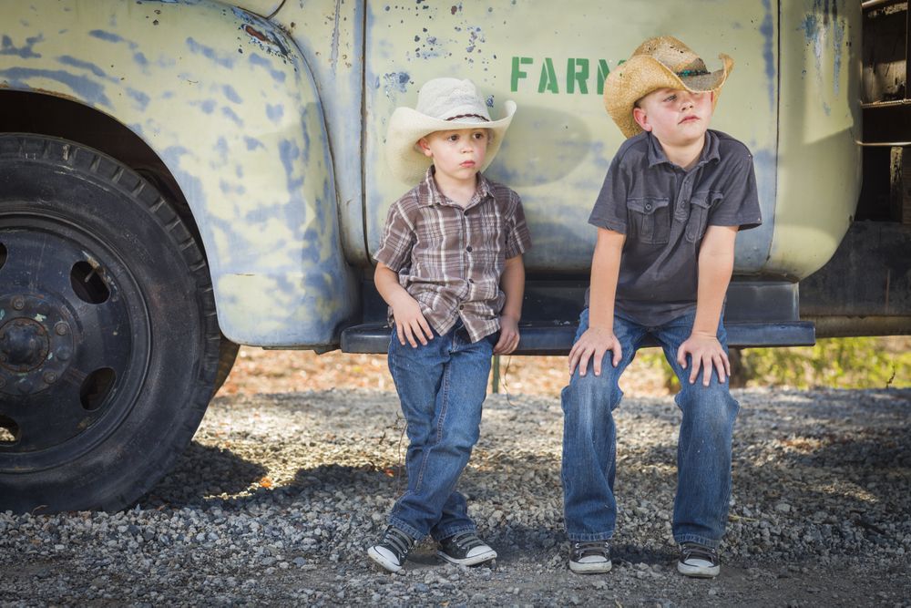 Two Boys Wearing Cowboy Hats Leaning Against Antique Truck.