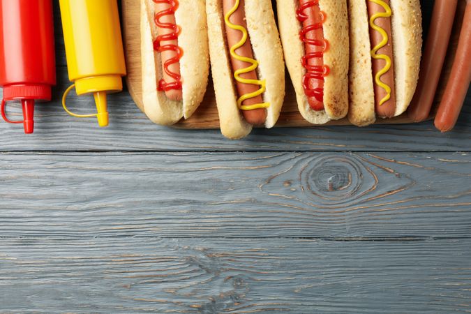 Tasty hot dogs and sauces on gray wooden background