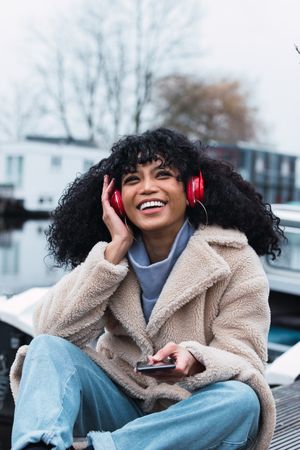 Cheerful woman listening to music at lakeside