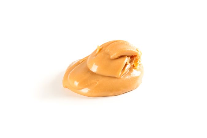 Creamy peanut butter isolated on light background. A traditional product of American cuisine
