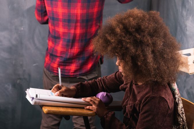 Multiracial teacher and pupil in classroom at math lesson