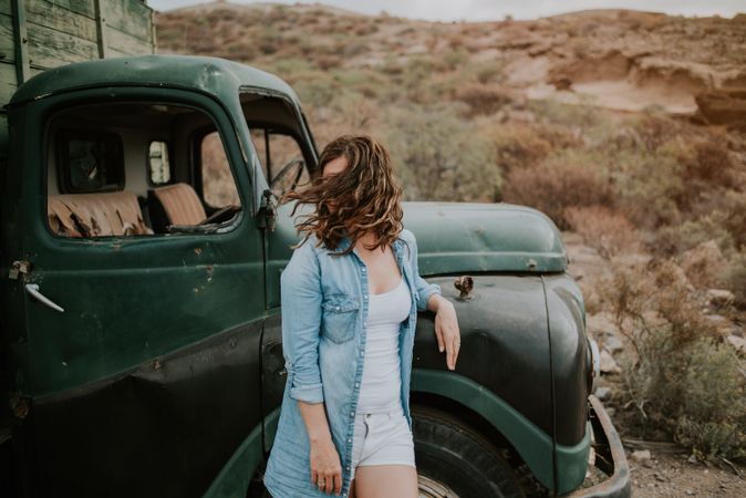 Relaxed female leaning on old truck