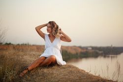 Female in summer dress relaxing by the lake at dusk