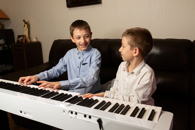 Two boys playing the keyboard and smiling