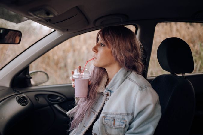 Stylish woman having drink in car