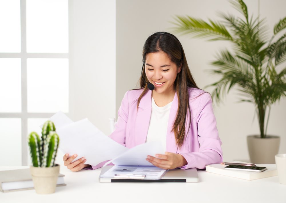portrait of asian business woman in pink jacket checking invoices at coworking