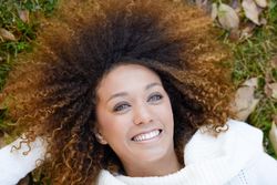 Smiling female in sweater lying down in park