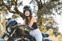 Attentive woman in helmet sitting on parked motorcycle at rural area