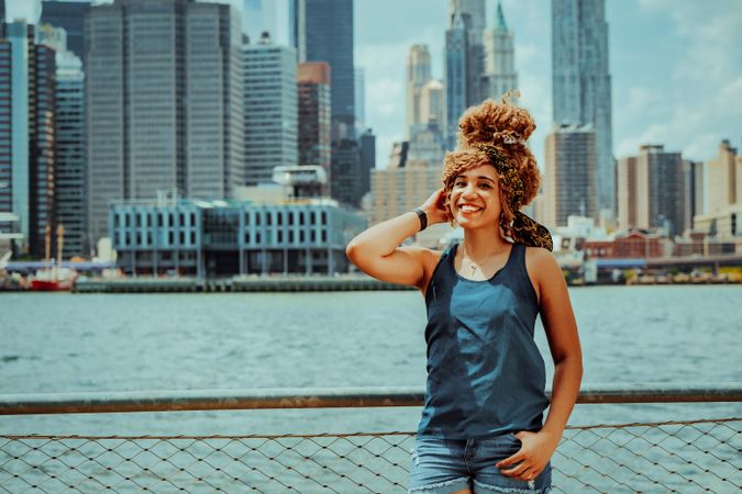 Black woman happy with her hand to her hair with Hudson River in the background, copy space