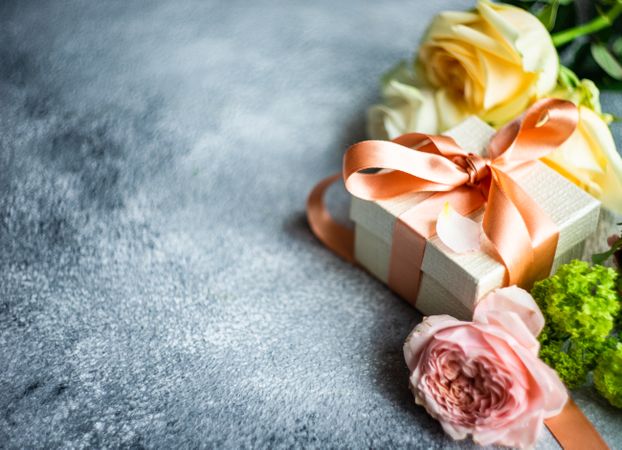 Pastel flowers on grey counter with gift with space for text