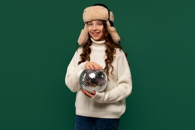 Smiling girl in winter hat holding small disco ball.