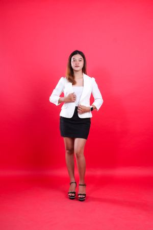 full body of young Asian woman wearing elegant white suit both hands holding suit