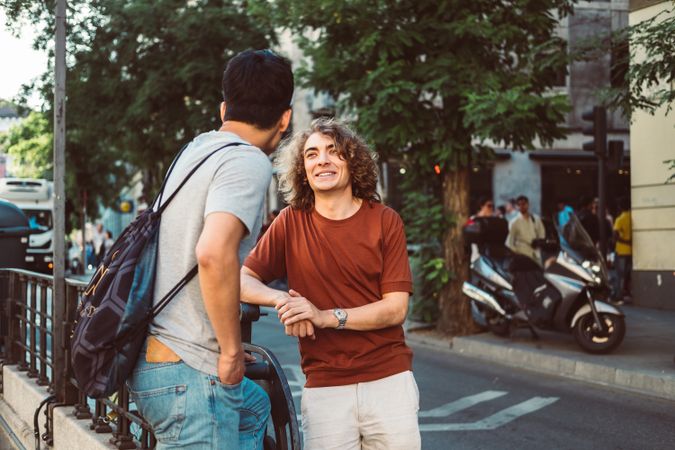 Cool multiracial male friends chatting while standing on street