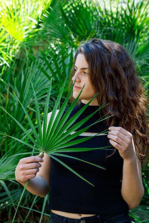 young female among green palm leaves