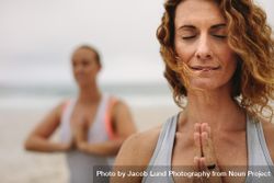Two fit women sitting with prayer hands outdoors near ocean 5zLRmb