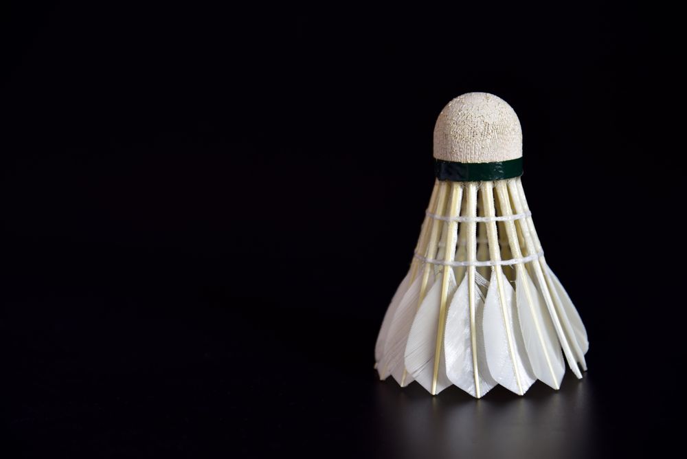 Single badminton shuttlecock in dark room, copy space
