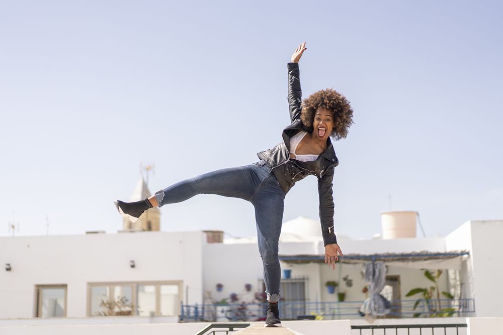 Funny Black woman balancing on wall