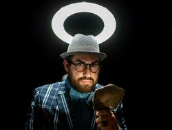 Fashion man in hat holding hand mirror and looking at camera