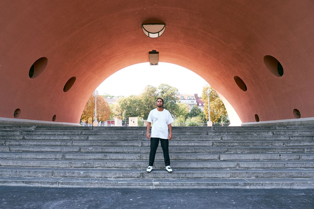 Trendy Black man posing near modern arch