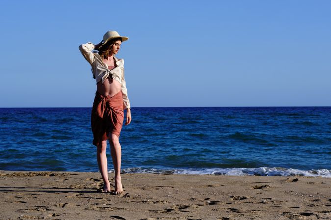 A fashion model with a hat at the beach before sunset