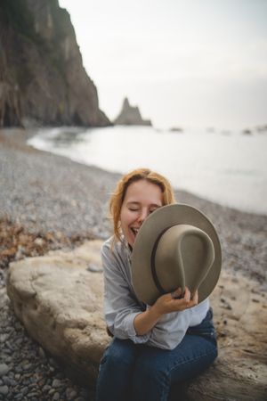 Woman resting on beach stone by sea
