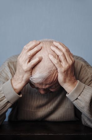 Mature man holding head in pain while feeling headache