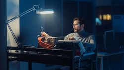 Professional Automotive Engineer in Glasses and Inspection Tools is Testing an Used Electric Engine in a High Tech Laboratory at Night.