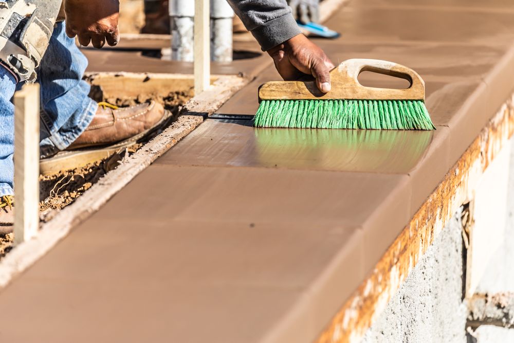 Construction Worker Using Brush On Wet Cement Forming Coping Around New Pool