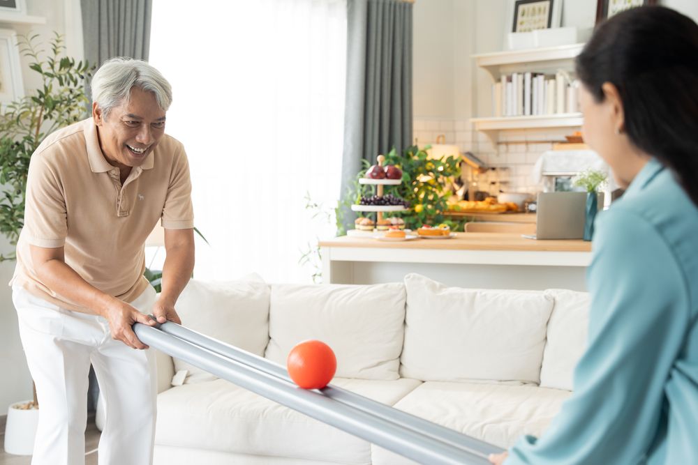 Asian couple playing rolling ball for practice balance and concentrate in the living room