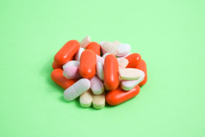 Variety of colorful medication and vitamins in center of green table with copy space