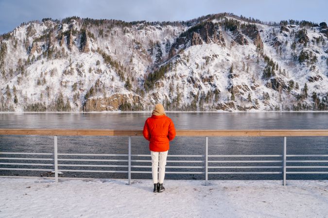 Woman enjoying landscape of river and snowy mountains