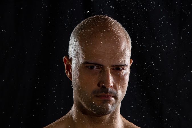 Serious bald man under rain