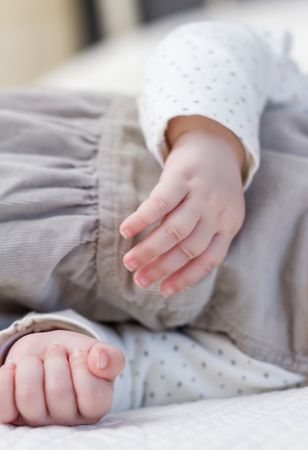 Hands closeup of baby girl sleeping over bedcover