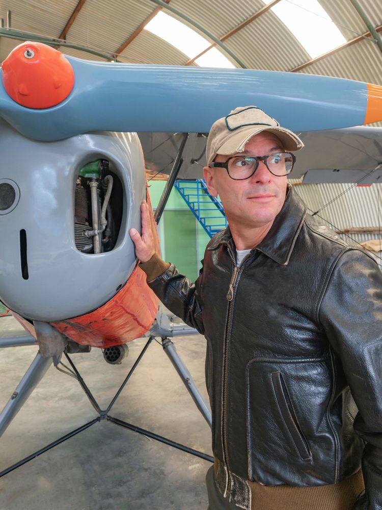 Confident pilot beside retro plane in hangar