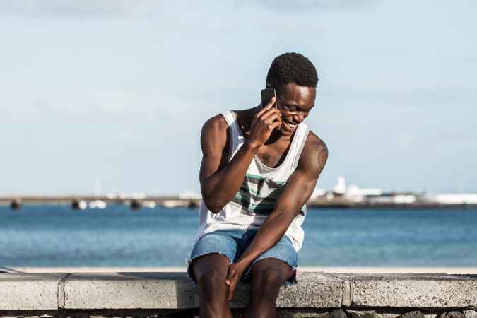 Man in tank top and shorts talking on the phone