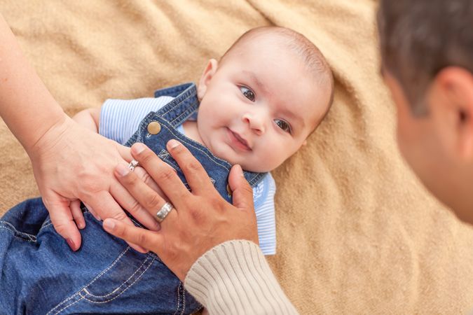Young  Couple Laying With Their Infant On A Blanket
