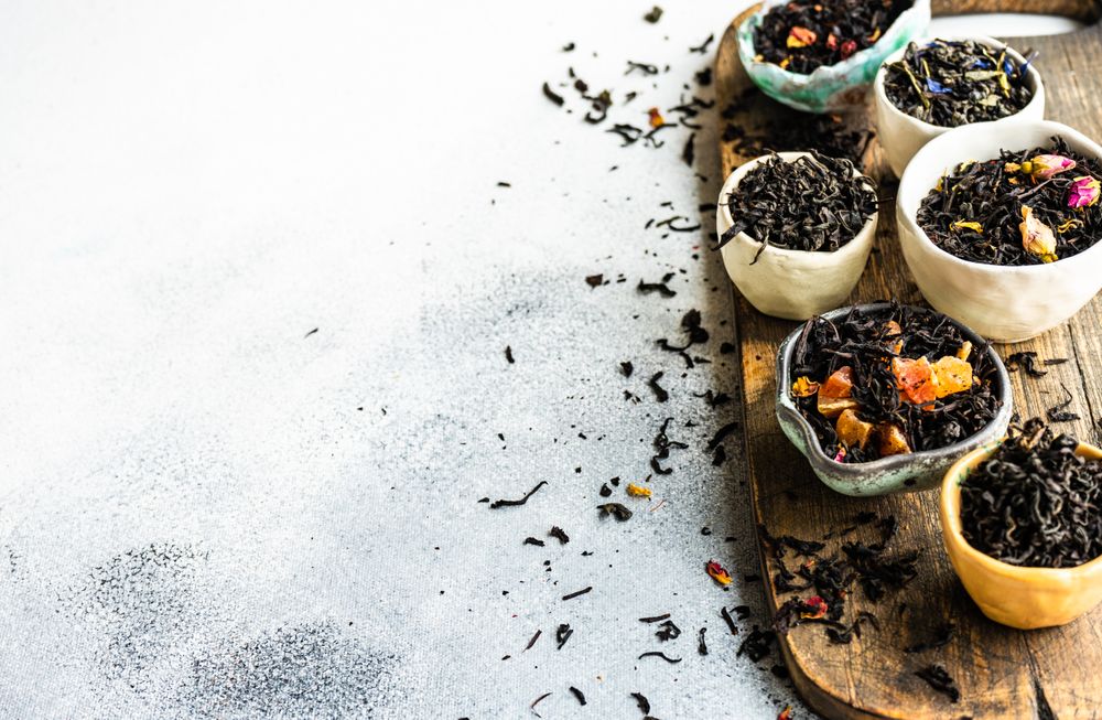 Bowls of loose leaf tea on board with copy space