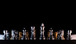 Silhouetted silver chess set with golden backdrop.
