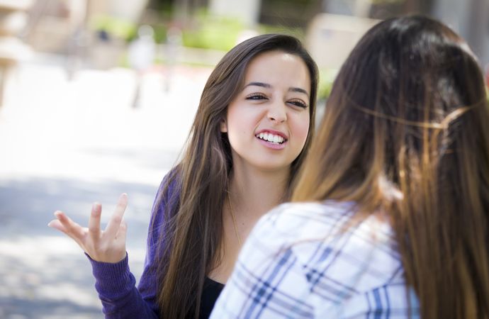 Expressive Young  Woman Sitting and Talking with Female Friend