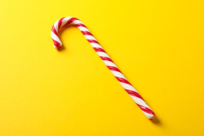 Sweet candy cane on yellow background, space for text