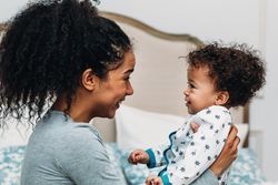 Mother smiling at her toddler son on bed
