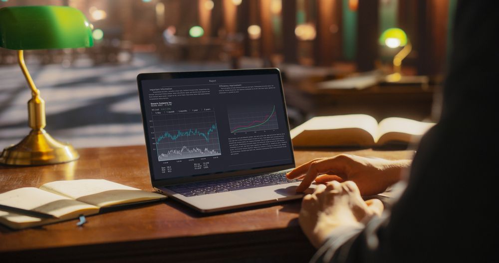Analytical Business Professional Reviewing Financial Data on a Laptop in a Classic Library