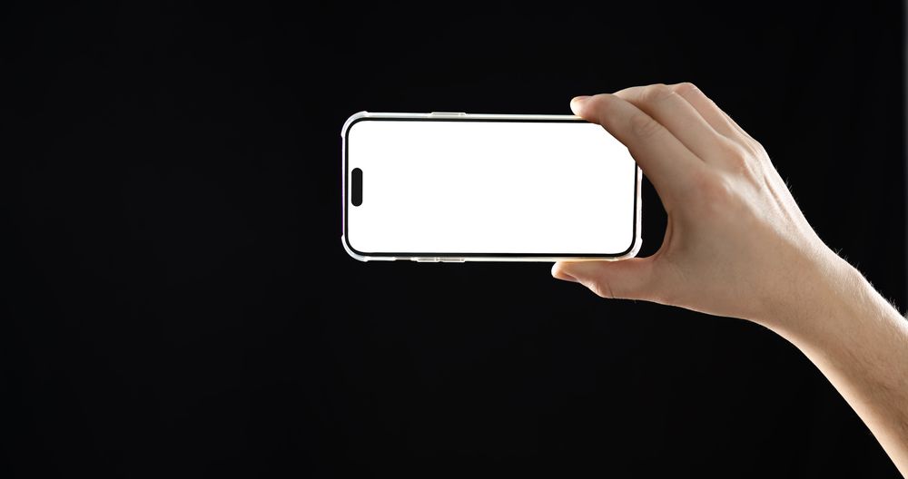 Hand holding phone on dark background