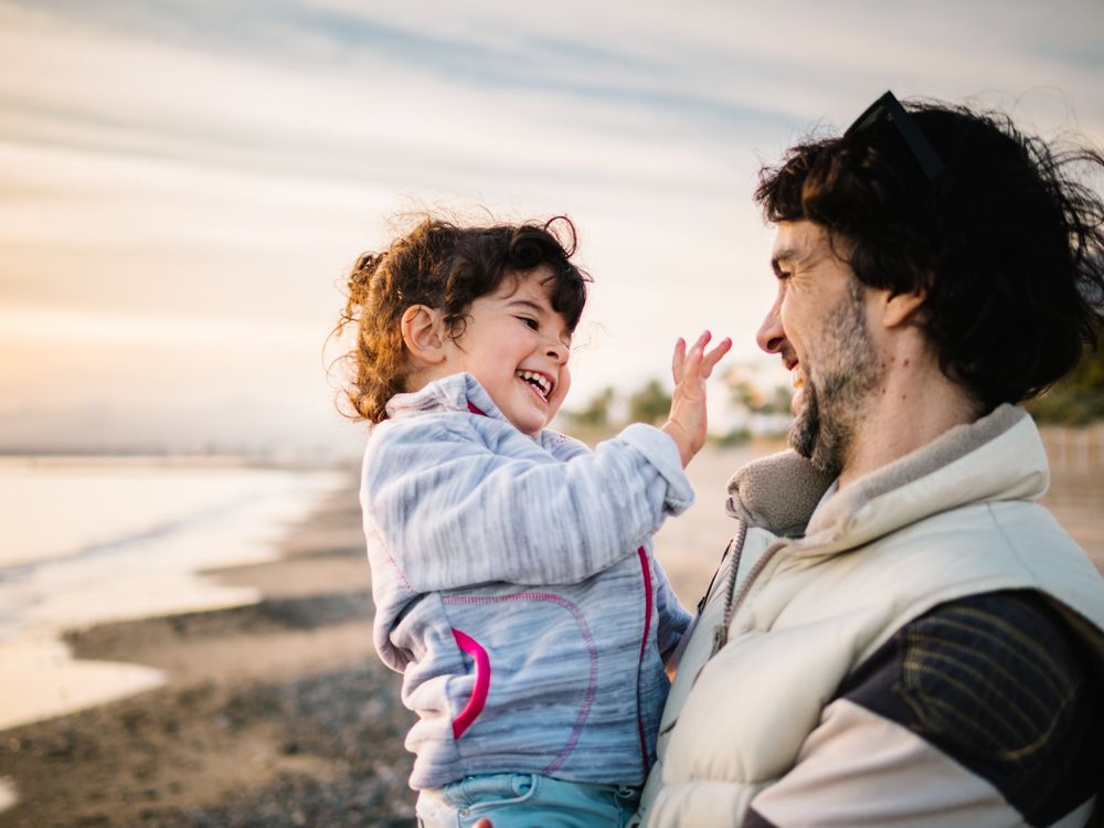 father holding little daughter at the beach
