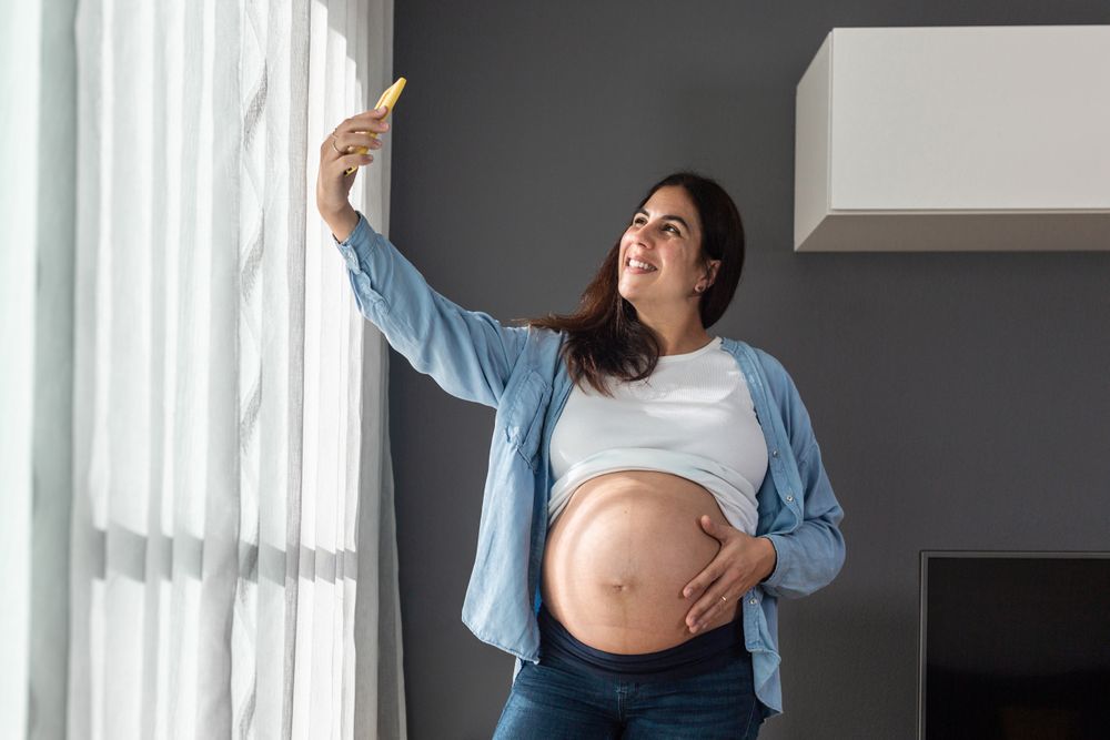 Pregnant woman taking selfie at home